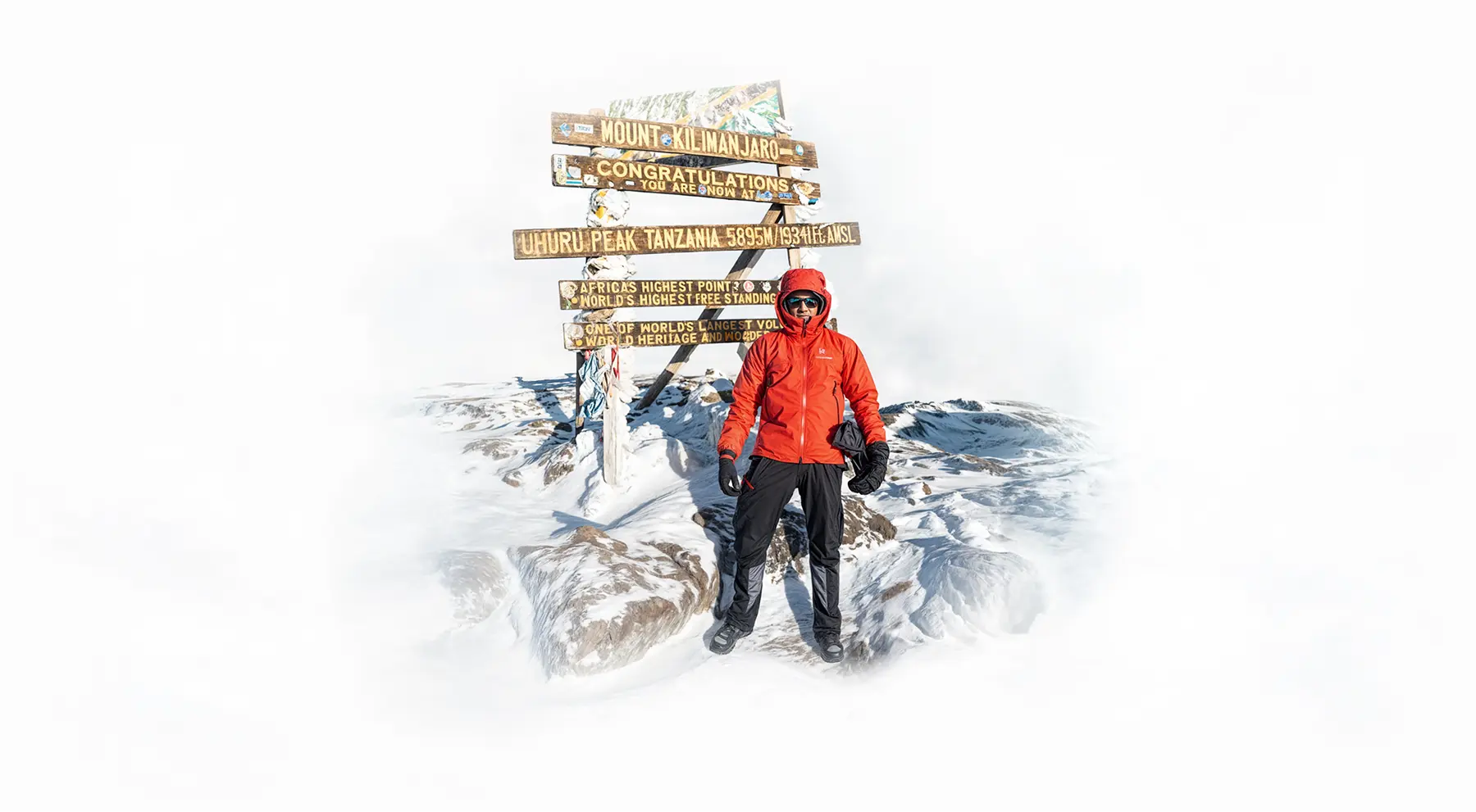 Alpinista accanto al cartello della vetta Uhuru Peak sul Kilimangiaro Alpinista accanto al cartello della vetta Uhuru Peak sul Kilimangiaro